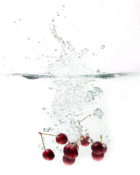 cerezas frescas que caen en el agua - black cherries fotografías e imágenes de stock