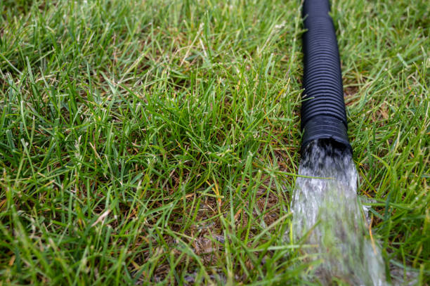 pompa di pompa di pompa residenziale scaricando acqua dalla fine di un tubo nero flessibile - siphon foto e immagini stock