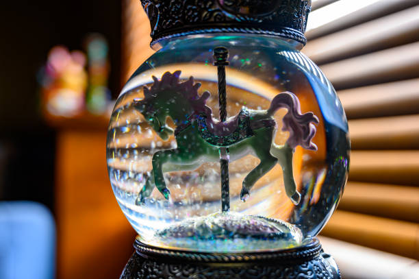 Glitter snow globe with carousel horse. Window blinds in background Decorative trinket with light in background and suspended glitter snow globe empty silhouette stock pictures, royalty-free photos & images