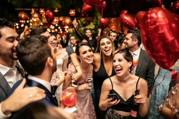 Photo of Groom and wedding guests laughing during party