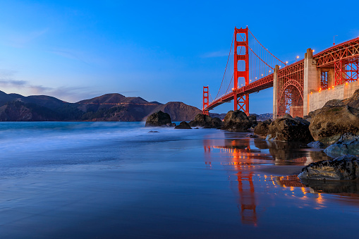 Famous Golden Gate Bridge view from the hidden and secluded rocky Marshall's Beach at sunset in San Francisco, California