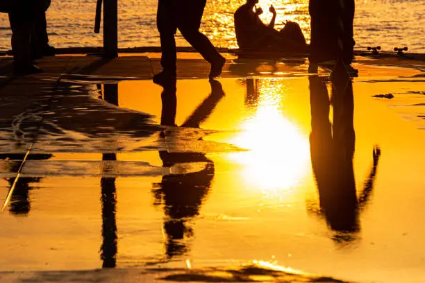 Silhouette of people reflected in a puddle on a sunset in Rio de Janeiro brazil