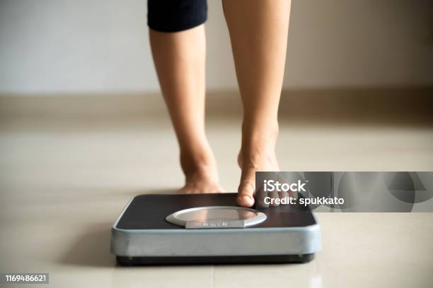 Female Leg Stepping On Weigh Scales Healthy Lifestyle Food And Sport Concept Stock Photo - Download Image Now