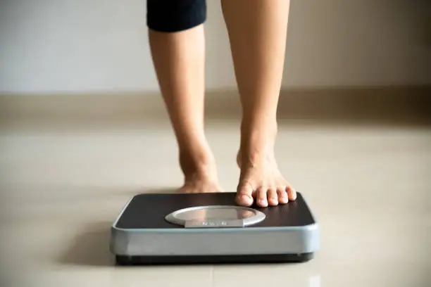 Photo of Female leg stepping on weigh scales. Healthy lifestyle, food and sport concept.