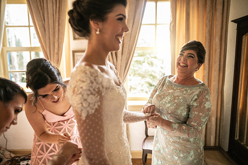 Damas de honor ayudando a la novia a vestirse para la ceremonia de la boda photo