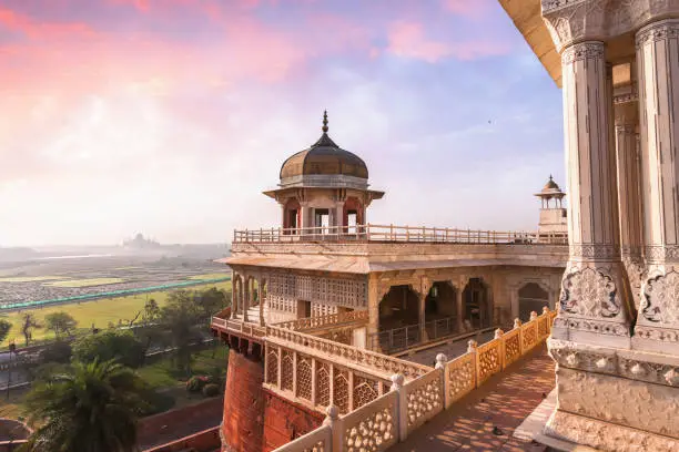 Agra Fort is a historical fort in the city of Agra in India being the main residence of the emperors of the Mughal Dynasty until 1638. View of the Musamman Burj dome of Agra Fort with view of Taj Mahal at the horizon