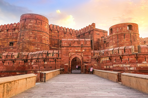 Agra Fort - Historic red sandstone fort of medieval India also known as the Red Fort Agra at sunrise. Agra Fort is a UNESCO World Heritage site in the city of Agra India.
