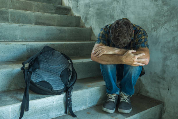 anti sexual discrimination and against homophobia campaign. Young sad and depressed college student man sitting on staircase desperate victim of harassment suffering bullying and abuse stock photo