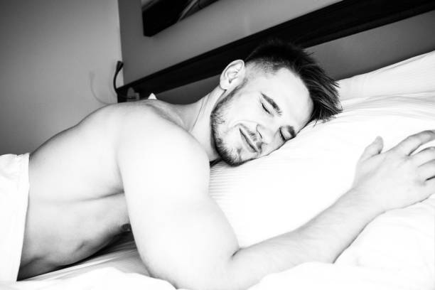 istock Good looking naked man lying in between white sheets 1169498306