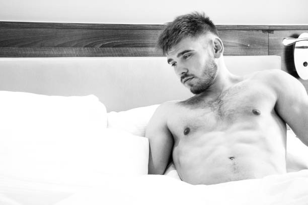 istock Good looking naked man lying in between white sheets 1169498320