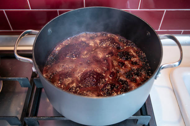 elderberry jam boiling in pot stock photo