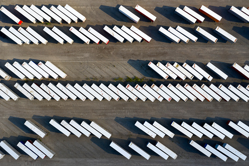 Rows of truck trailers and shiping containers in freight yard viewed from above.