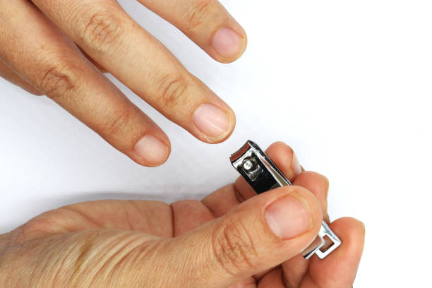 istock Woman cutting nails using nail clipper isolated on black background. 1169507389