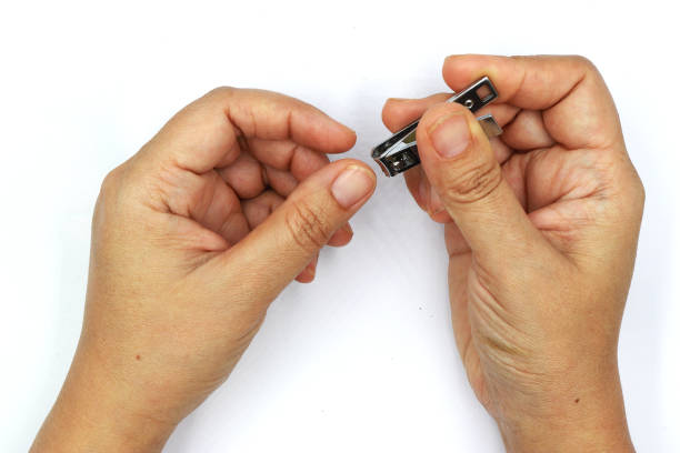 istock Woman cutting nails using nail clipper isolated on black background. 1169507588