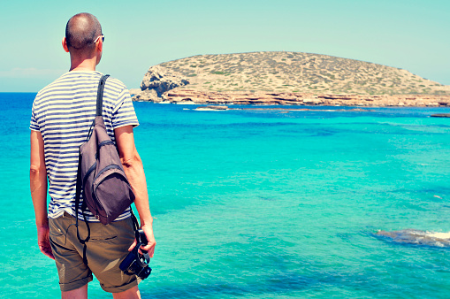 hombre mirando al mar y a la isla Illa des Bosc, en Ibiza, España photo