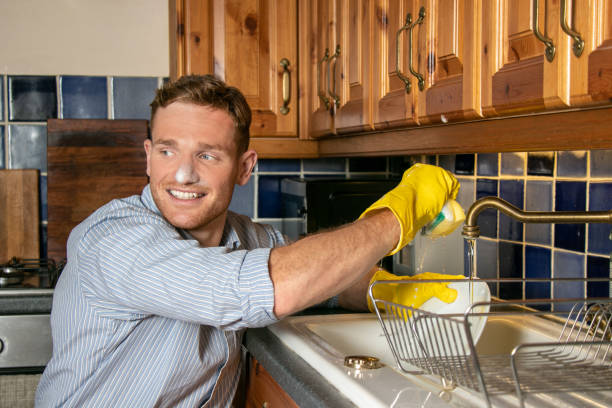 istock Handsome young man washing dishes in kitchen 1169514884