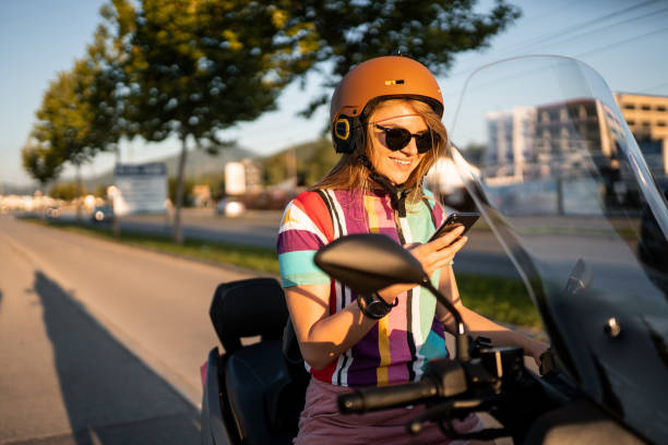 istock Beautiful young girl on scooter using phone 1169515111
