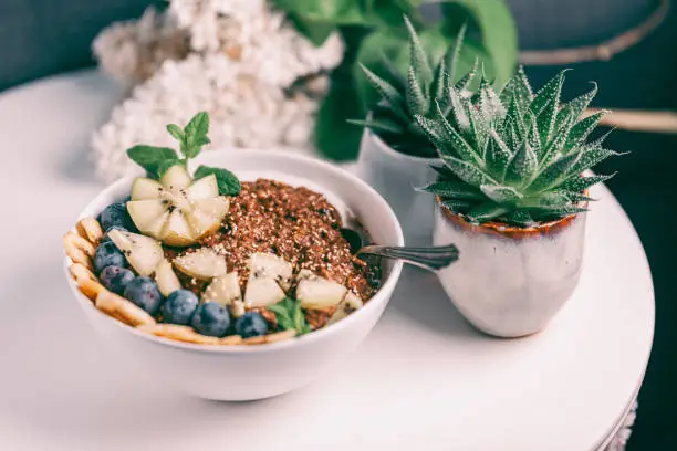 Photo of Organic Chocolate and Buckwheat Porridge Bowl topped with Banana, Blueberries, Kiwi and popped amaranth