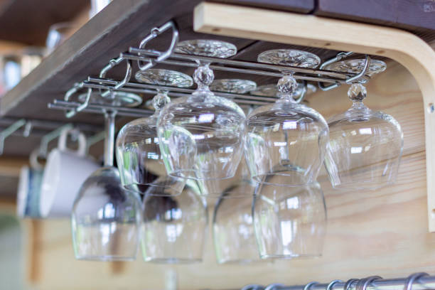 istock Clean empty wine glasses in row hang on shelf bar in light sunshine. 1169522254
