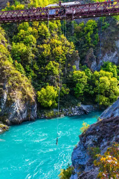 Bungee jumping attraction on the bridge over the picturesque mountain river. Exotic journey to the South Island of New Zealand. Concept of active, extreme and ecological tourism