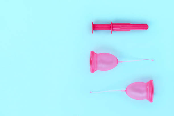 istock Two pink menstrual cups and an applicator for their introduction on a blue background 1169526362