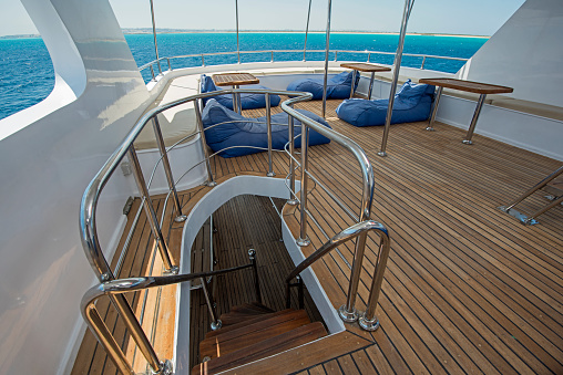 Rear sundeck of a large luxury motor yacht with chairs sofa table and tropical sea view background