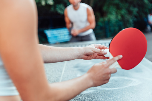 Cropped image of woman serving ball on table tennis while playing with man