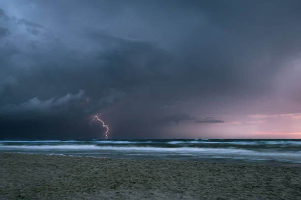 istock Lightning bolt from a thunderstorm over sea at sunset 1169530852