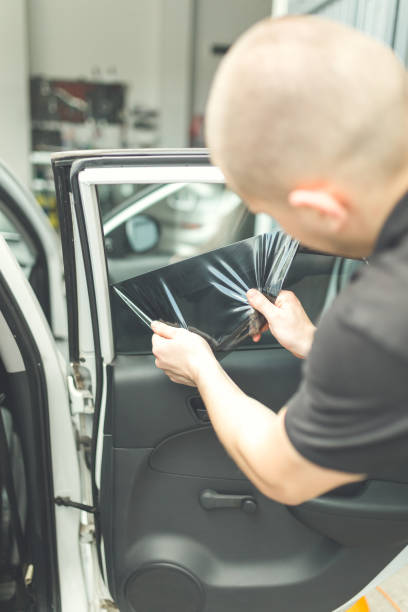 istock Process of removing glass protection tinted foil from side car window. 1169533178