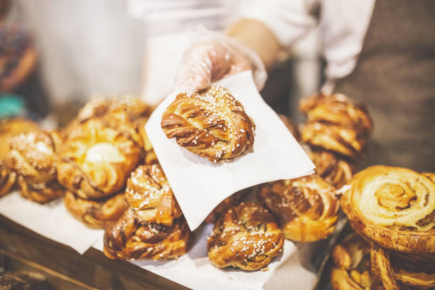 istock Man hand holding golden colored pastry rolls in bakery. 1169533855