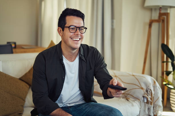 istock Cheerful smiling man enjoying watching television at home 1169539408