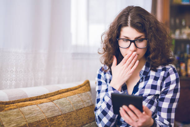 istock Surprised woman sitting on couch and using tablet 1169541727