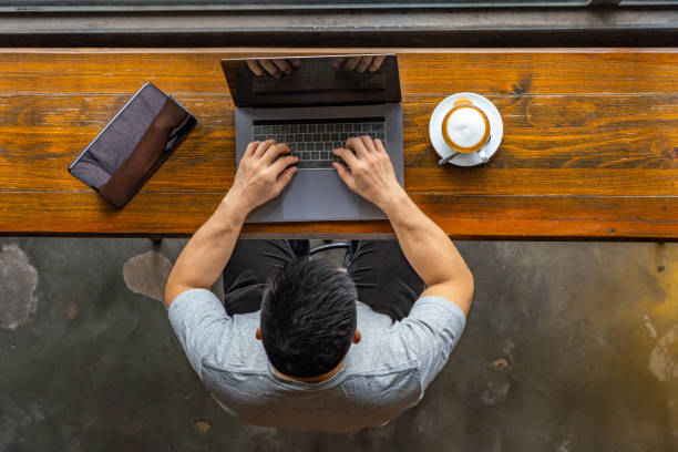 istock Asian freelancer typing laptop keyboard next to tablet at coffeeshop 1169544223