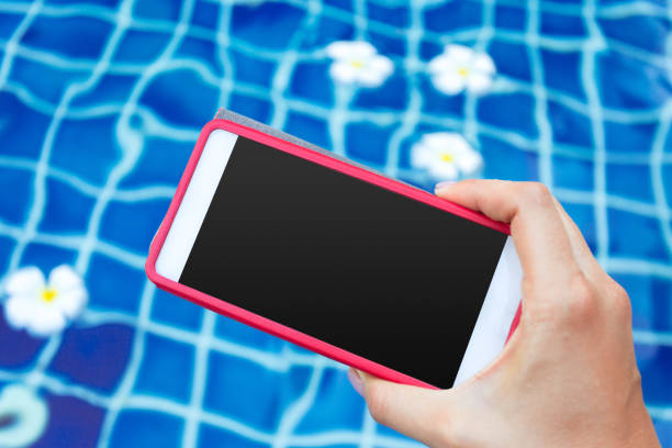 istock Smartphone with black screen near pool. Vacation concept 1169544995