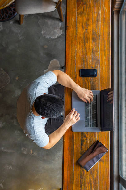 istock Top view of Asian freelancer using laptop on wooden table 1169546245