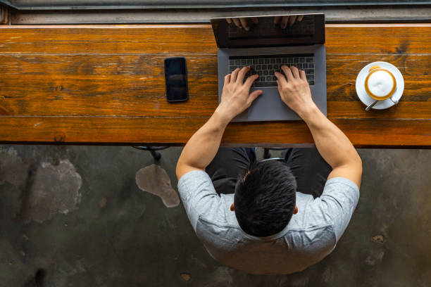 istock Muscled Asian man freelancing on laptop at rustic coffeeshop 1169547745