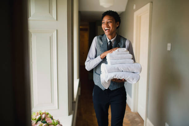 Staying Positive While Working A front view of a woman working in a hotel laughing and looking out the window while holding fresh towels for a hotel room. room service stock pictures, royalty-free photos & images