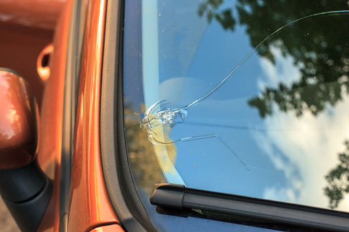 Broken car windshield glass from stone. Damaged windscreen on vehicle, close up