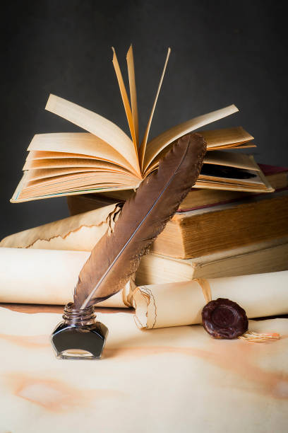istock Papyrus scrolls on a table top with books, pen and inkwell 1169549510