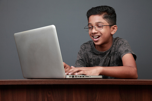 Young boy of Indian origin using a laptop