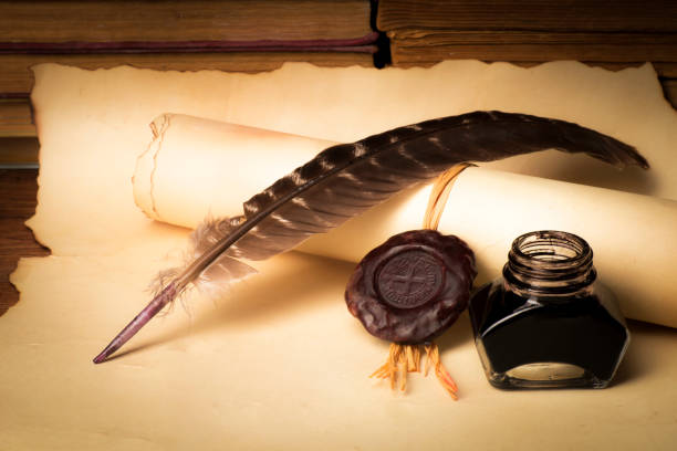 istock Papyrus scrolls on a table top with books, pen and inkwell 1169549599