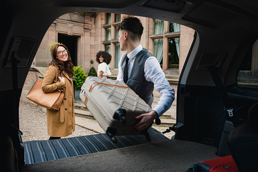 Two friends arrive at a luxury hotel where the hotel staff is helping the women bring their luggage inside.