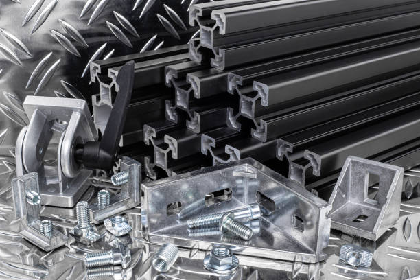 istock stack of black anodized aluminum extrusion bars, connector, joint, screw , slot nut and angle bracket silver shiny diamond plate background. Construction metal steel factory concept. 1169552114