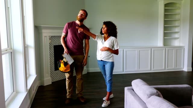 Young pregnant woman talks with contractor in new home