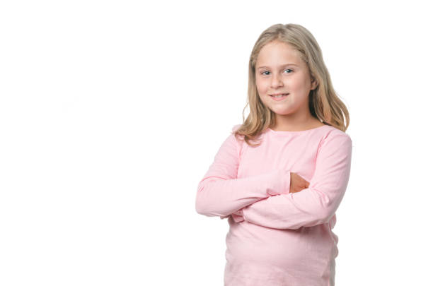 Eight year old blond little girl smiling and with her arms crossed on white background
