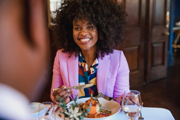 Contented Hotel Diner A beautiful woman smiling while sitting at a hotel dining room table with an unrecognisable man. black people eating stock pictures, royalty-free photos & images