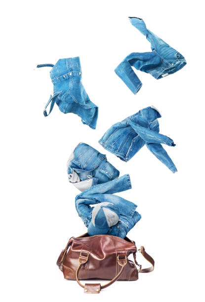 jeans vestiti che volano dal bagaglio a mano in pelle broun isolato su uno sfondo bianco - borsa monospalla foto e immagini stock