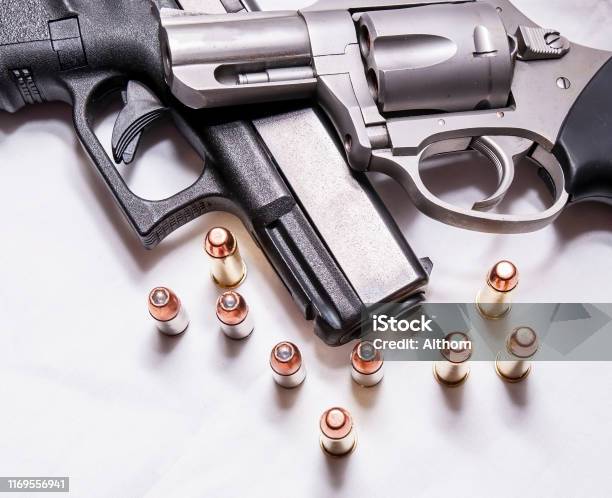 Một Khẩu Súng Lục 357 Magnum Mũi Hếch Không Gỉ Trên Đỉnh Của Một Khẩu Súng Lục 9mm Màu Đen Với Một Số Viên Đạn Cho Mỗi Cỡ Nòng Trước Mặt Họ Một Khẩu Súng Lục 357 Magnum Mũi Hếch Không Gỉ Trên Đỉnh Của Một Khẩu Súng Lục 9mm Màu Đen Với Một Số Viên Đạn Cho Mỗi Cỡ Nòng Trước Mặt Họ