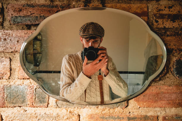 A young man taking a self portrait in a mirror in his bathroom.