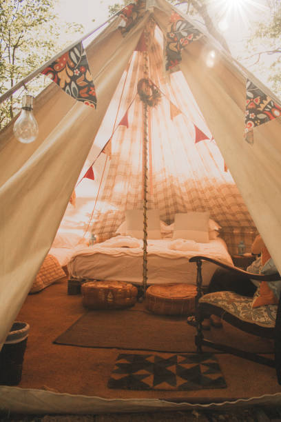 Cozy Glamping Tent Interior of a clamping tent from outside of the tent looking in. There is a young female adult sitting in a chair while relaxing in the tent. glamping photos stock pictures, royalty-free photos & images